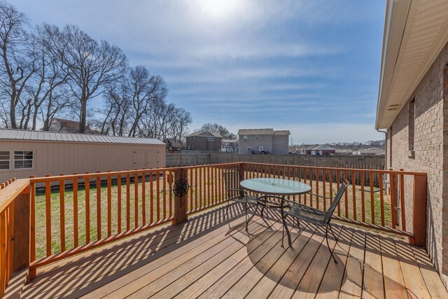 wooden terrace with a yard, an outdoor structure, and a fenced backyard