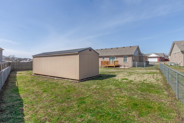 view of yard featuring an outbuilding, a storage unit, a fenced backyard, and a wooden deck