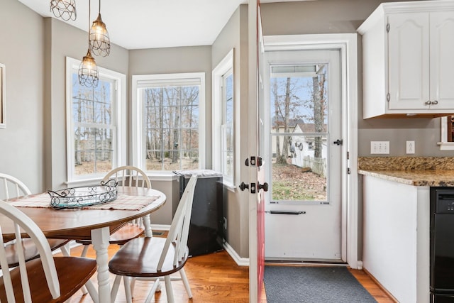 dining space with a wealth of natural light, baseboards, and light wood-style flooring