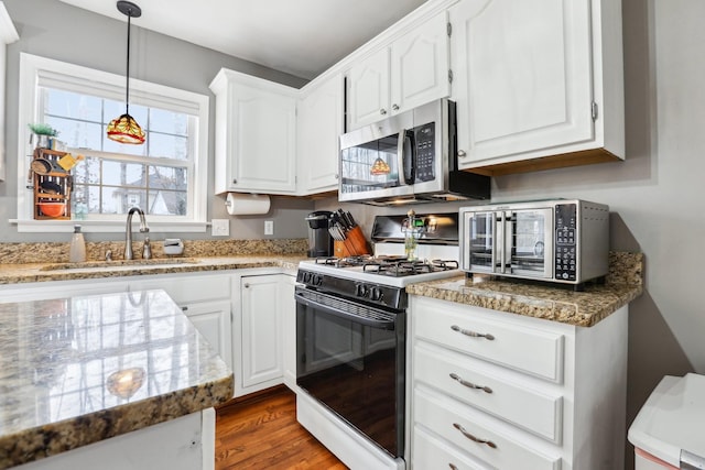 kitchen with stainless steel microwave, white cabinets, gas range oven, and a sink