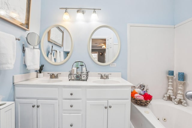 bathroom with double vanity, a tub with jets, and a sink