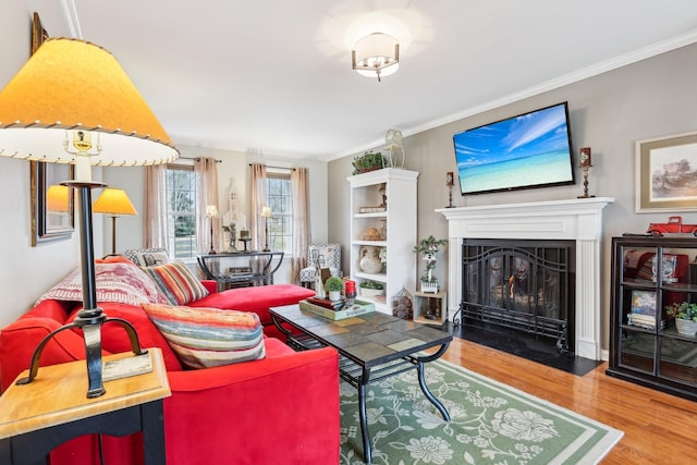 living area featuring a fireplace with flush hearth, wood finished floors, and ornamental molding