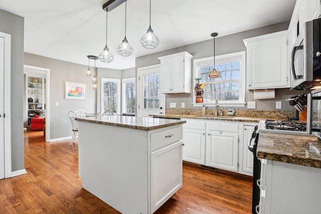 kitchen featuring stainless steel microwave, white cabinets, a kitchen island, and a sink