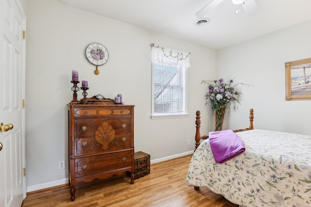 bedroom with a ceiling fan, visible vents, wood finished floors, and baseboards