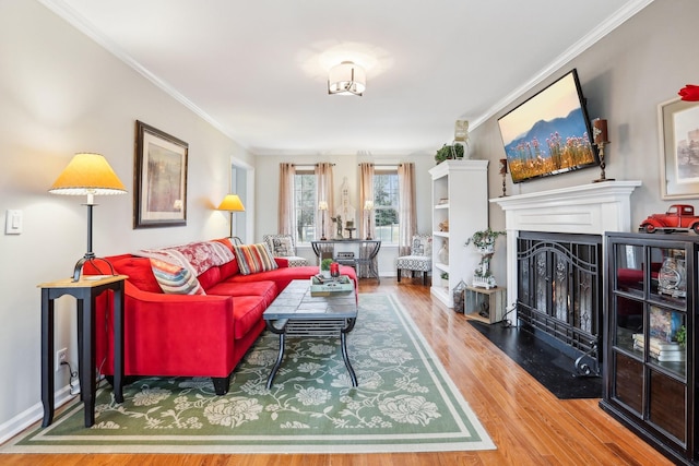 living area with a fireplace, crown molding, baseboards, and wood finished floors