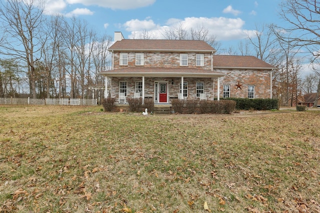 view of front of house featuring covered porch, a chimney, a front yard, and fence