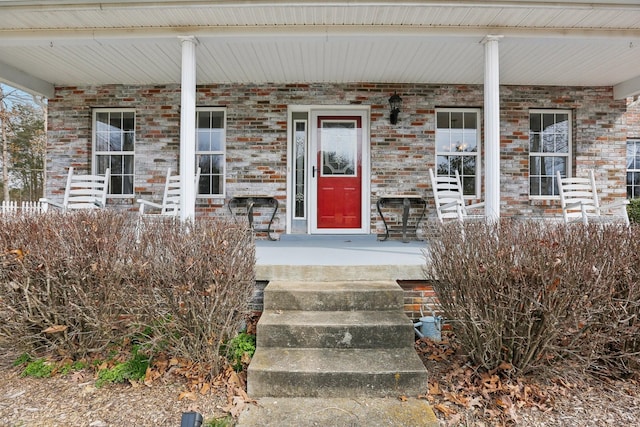 entrance to property with brick siding and a porch