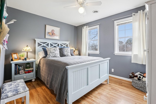 bedroom featuring ceiling fan, visible vents, baseboards, and wood finished floors