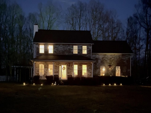 view of front of property with stone siding, covered porch, and a chimney