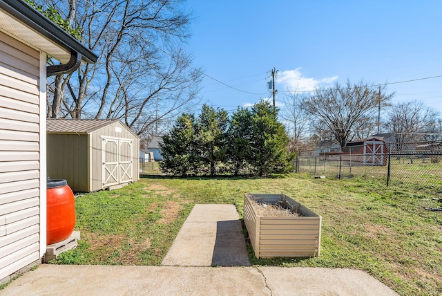 view of yard featuring a storage shed, a vegetable garden, fence, and an outbuilding