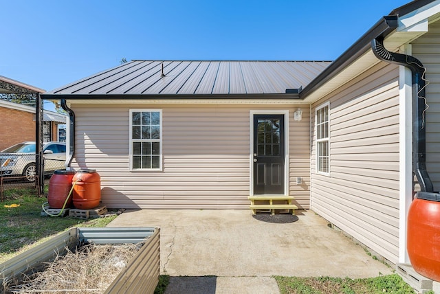 property entrance featuring metal roof, a patio, and fence