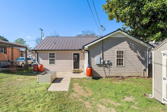 rear view of property with metal roof, a lawn, and fence