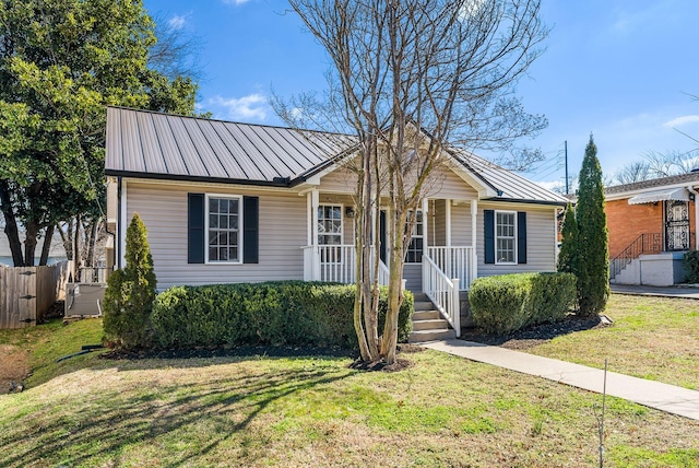 view of front of home with a standing seam roof, a front lawn, covered porch, and metal roof