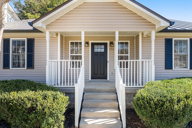 entrance to property with a standing seam roof, a porch, and metal roof