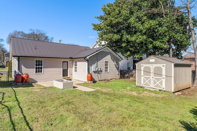 back of house with an outbuilding, fence, a shed, a yard, and metal roof