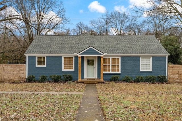 view of front facade with fence, brick siding, and a shingled roof