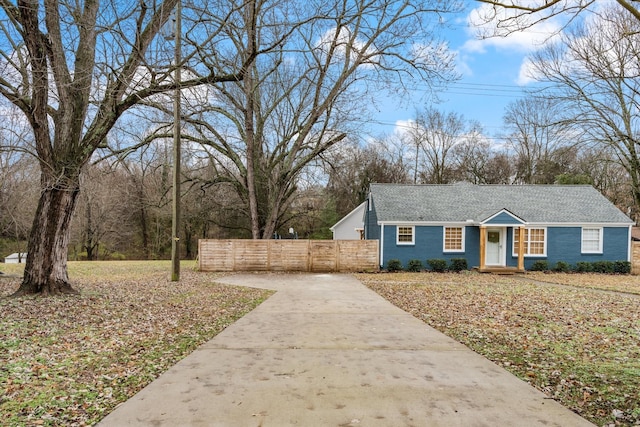 view of front of home with brick siding, concrete driveway, and fence