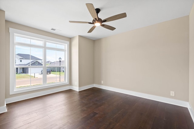 spare room featuring a ceiling fan, visible vents, baseboards, and dark wood-style flooring