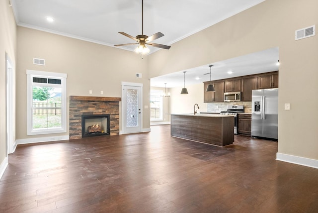 unfurnished living room with dark wood-type flooring, a healthy amount of sunlight, visible vents, and a sink