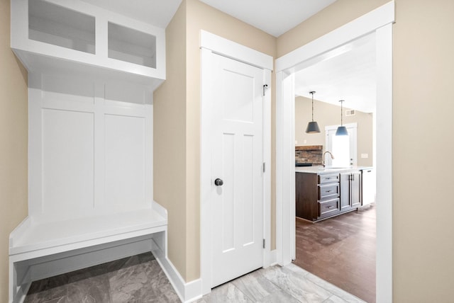 mudroom with visible vents, baseboards, marble finish floor, and vaulted ceiling