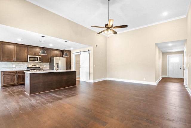 kitchen with dark wood-style floors, a barn door, appliances with stainless steel finishes, light countertops, and ceiling fan