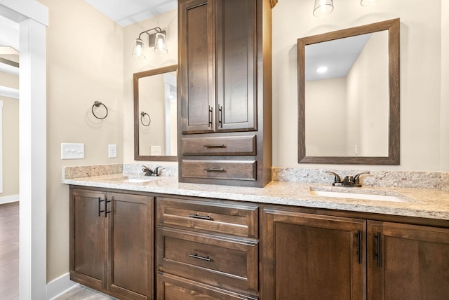 bathroom with a sink, baseboards, and double vanity