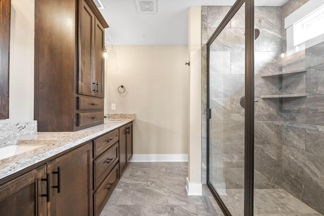 bathroom featuring visible vents, baseboards, double vanity, a shower stall, and marble finish floor