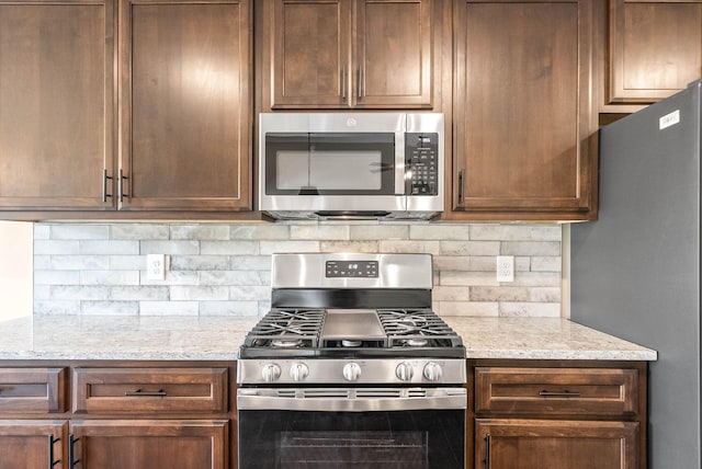 kitchen featuring decorative backsplash, appliances with stainless steel finishes, and light stone countertops