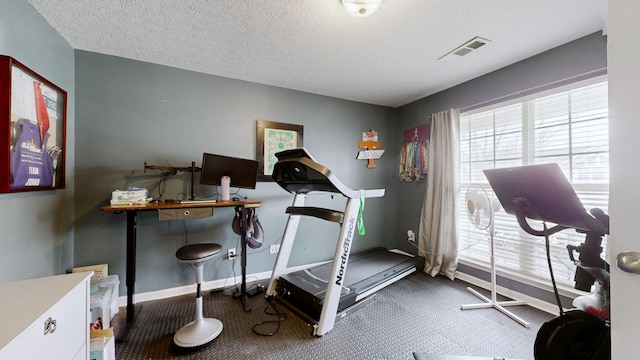 workout room with visible vents, a textured ceiling, and baseboards