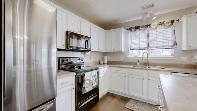 kitchen with visible vents, a sink, black appliances, white cabinets, and light countertops