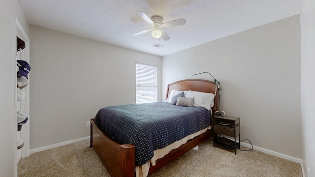 carpeted bedroom with visible vents, ceiling fan, a textured ceiling, and baseboards