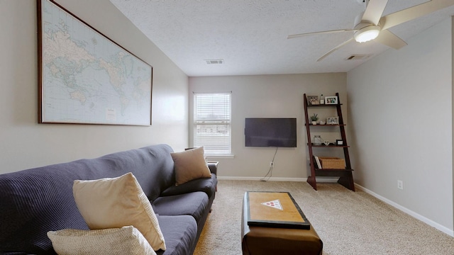 living room featuring visible vents, baseboards, carpet, a textured ceiling, and a ceiling fan