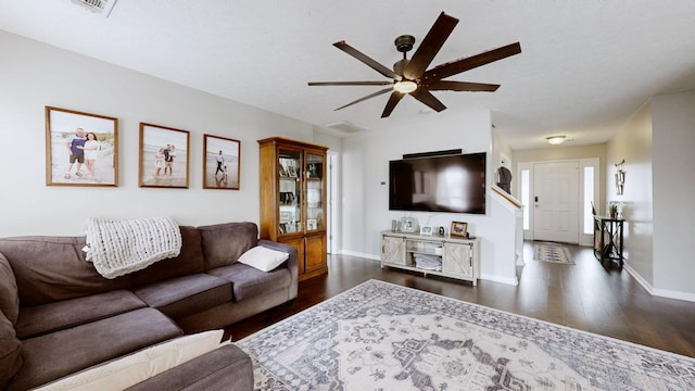 living area with baseboards, dark wood-type flooring, and ceiling fan