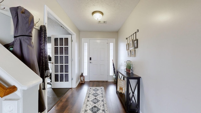 foyer featuring visible vents, a textured ceiling, and dark wood-style flooring