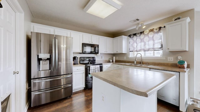 kitchen with black appliances, white cabinets, visible vents, and a sink