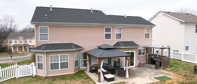 rear view of house with roof with shingles, a gazebo, a fenced backyard, a yard, and a patio