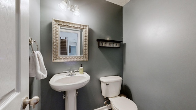 half bathroom with toilet, baseboards, and a sink