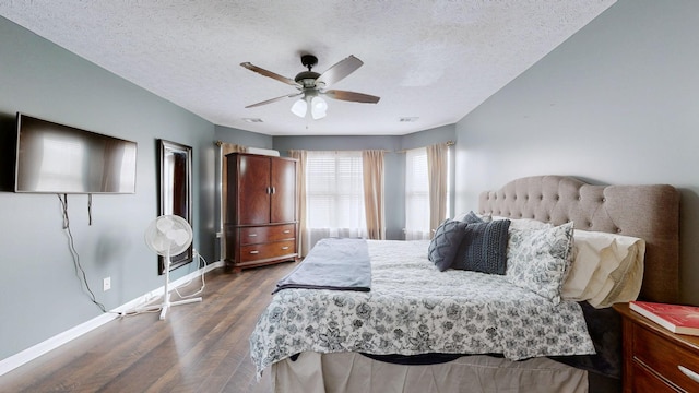 bedroom featuring visible vents, a textured ceiling, wood finished floors, baseboards, and ceiling fan