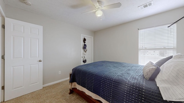 bedroom featuring a ceiling fan, baseboards, visible vents, a textured ceiling, and carpet flooring