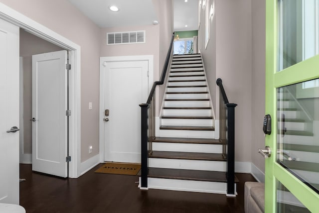 foyer entrance with visible vents, stairs, baseboards, and wood finished floors