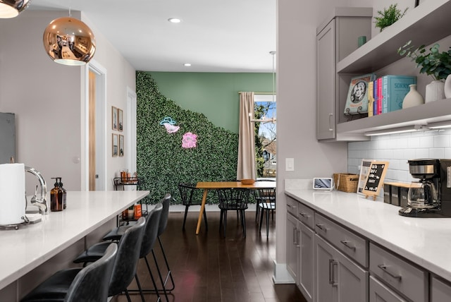 kitchen with open shelves, a kitchen breakfast bar, backsplash, and gray cabinetry