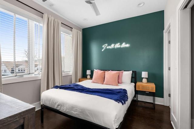 bedroom featuring a ceiling fan, visible vents, wood finished floors, and baseboards