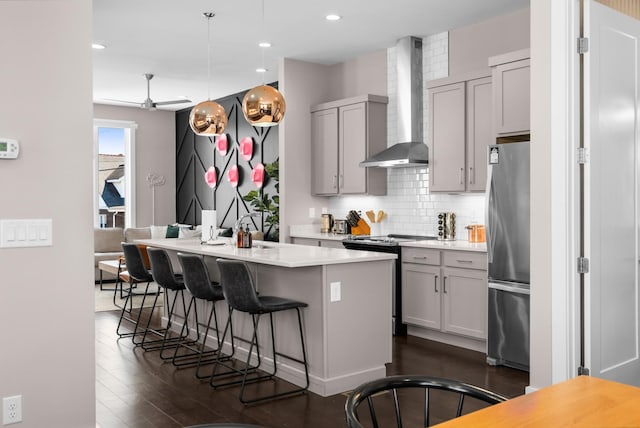 kitchen featuring backsplash, light countertops, freestanding refrigerator, electric range, and wall chimney exhaust hood