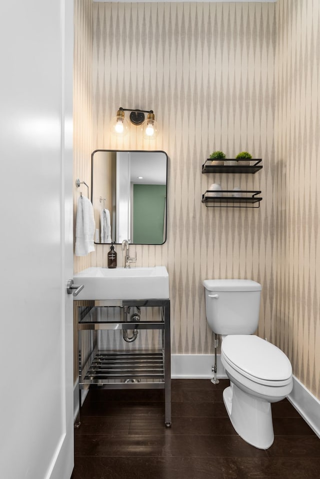 half bath featuring toilet, wood finished floors, and baseboards