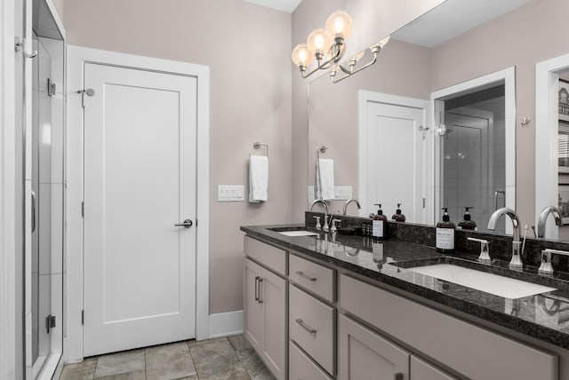 bathroom with double vanity, a stall shower, baseboards, and a sink