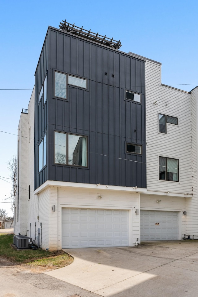 view of front of house featuring central AC unit, board and batten siding, concrete driveway, and a garage