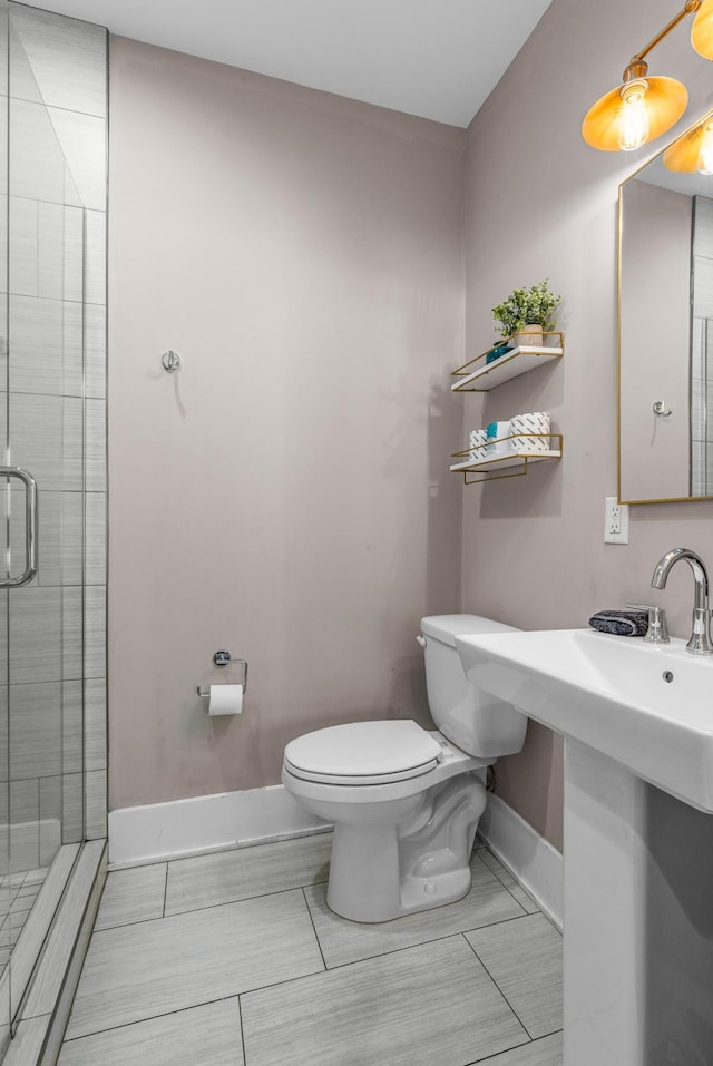 full bathroom featuring toilet, baseboards, and a stall shower