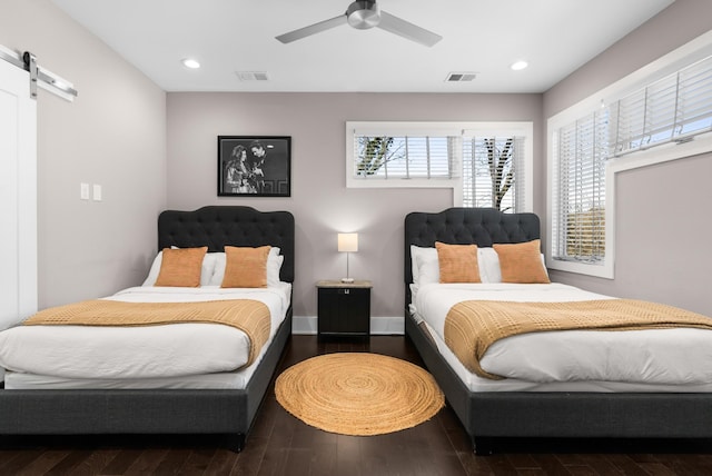 bedroom with visible vents, recessed lighting, a barn door, and wood finished floors