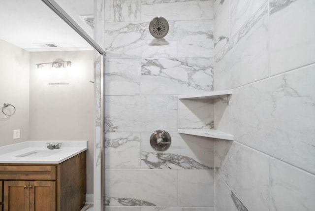 full bathroom with vanity, visible vents, and a tile shower