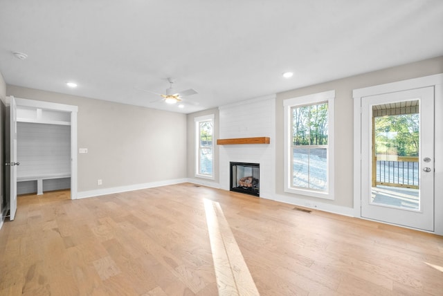 unfurnished living room featuring a wealth of natural light, a fireplace, and light wood-style floors